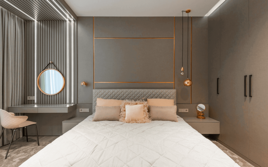 Een slaapkamer met perzikkleurige kussens op een lichtbruine achtergrond en goudkleurige metalen accenten