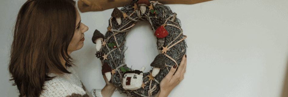 A woman hang a wreath on a wooden hook