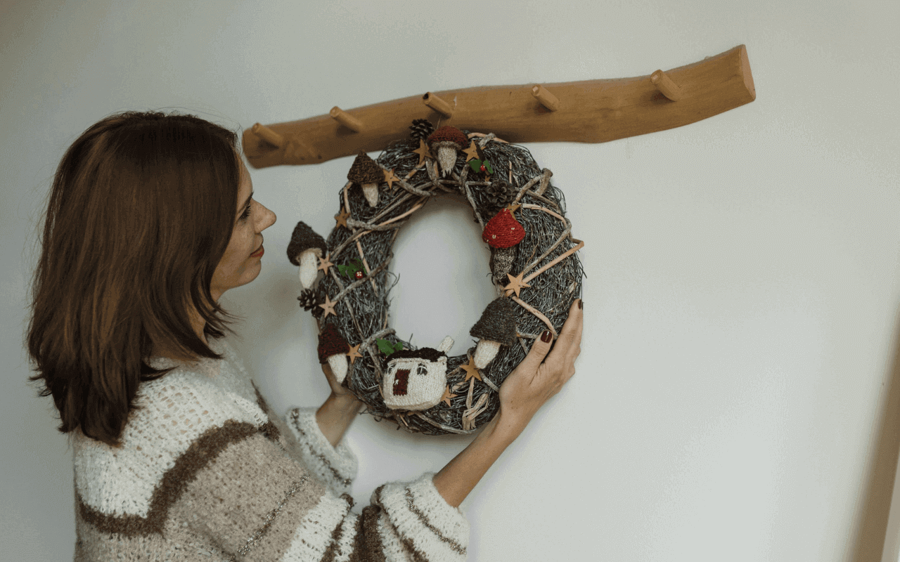 A woman hang a wreath on a wooden hook