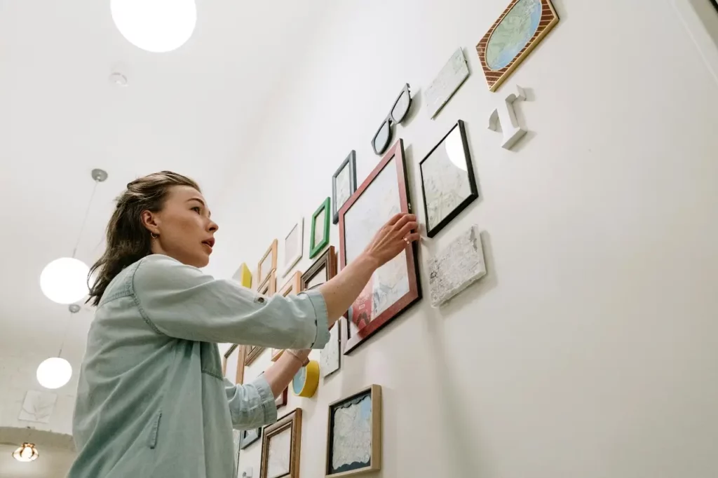 woman-hanging-pictures-on-the-wall-creating-a-gallery-wall