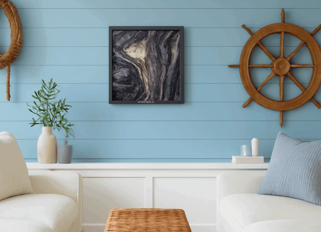 "Nautical-themed living space with a ship’s wheel wall decoration, a black-framed abstract stone print, light blue paneled walls, and white armchairs with minimalist accessories.